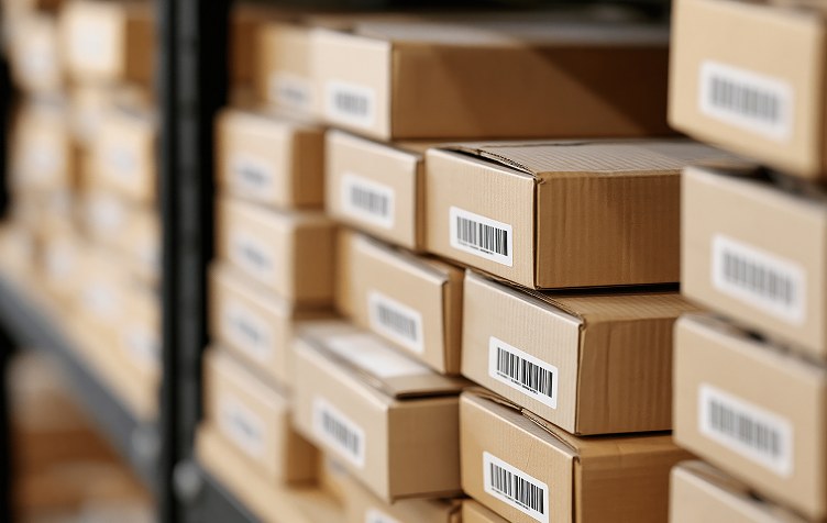 Cartons labelled with barcodes stacked on warehouse shelving
